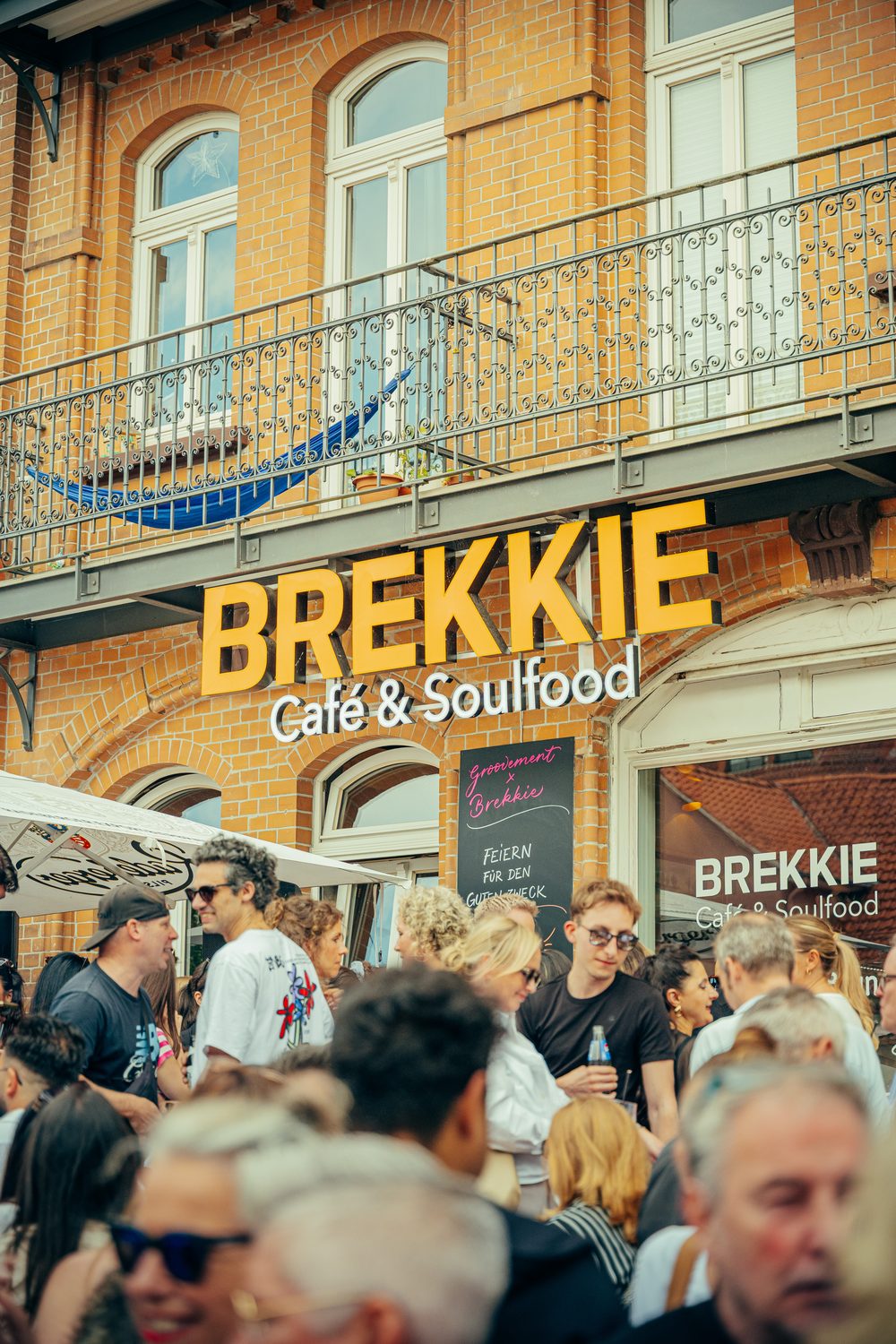 Volles Haus vor dem Brekkie — Gäste vor der goldenen Café-Fassade