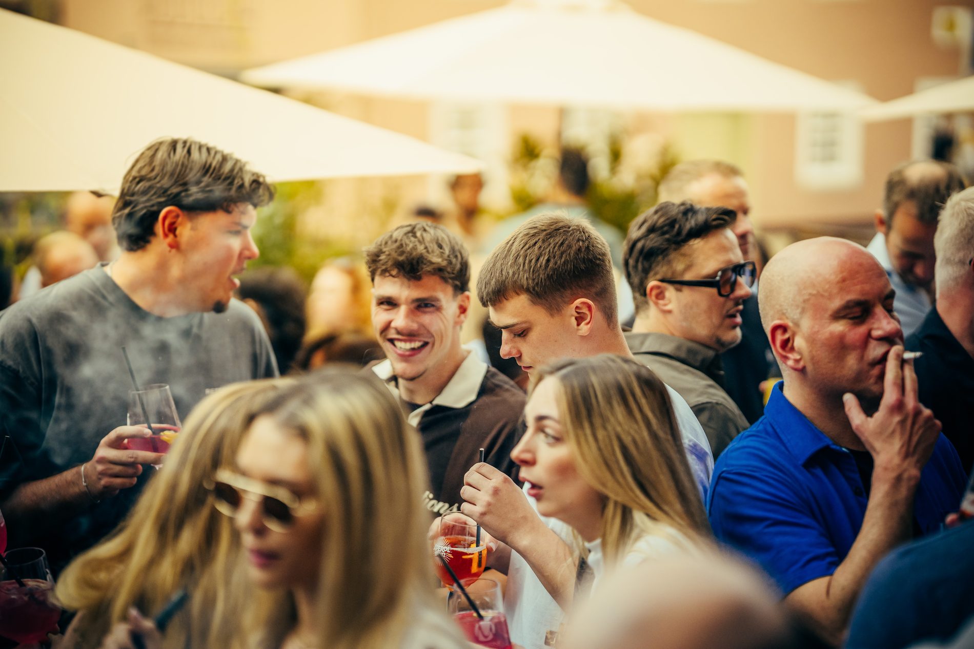 Ausgelassene Stimmung — Gäste lachen mit Drinks in der Sonne